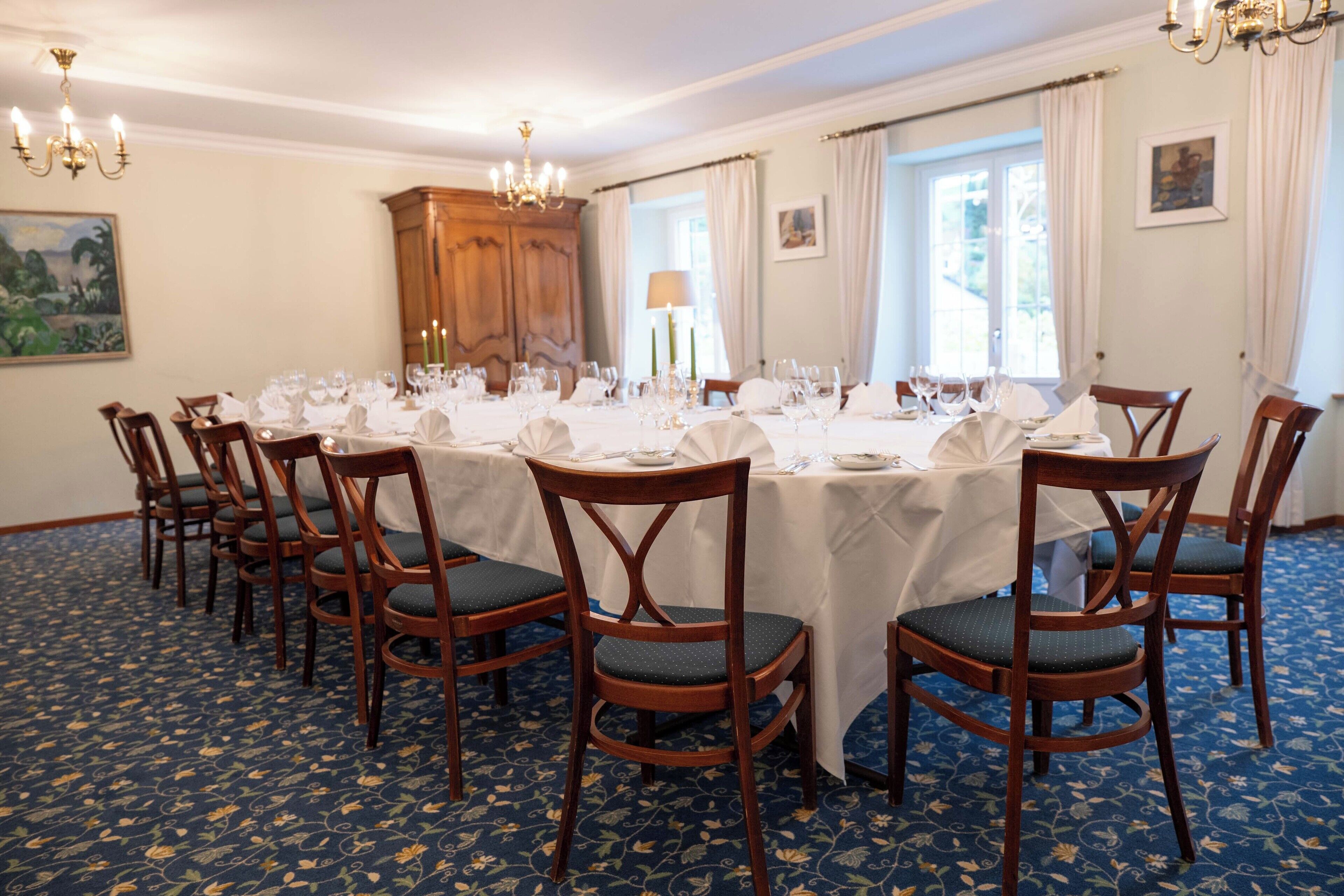 Ein Esszimmer mit einem langen Tisch, der für eine Mahlzeit gedeckt ist, umgeben von Holzstühlen mit grünen Kissen.