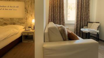 A hotel room with a bed, a nightstand, a lamp, a chair, and a window with curtains.