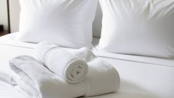 Una cama bien hecha con sábanas y almohadas blancas.