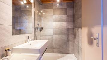 A modern bathroom with a large sink, mirror, and shower.