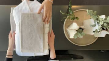 A person holding a white towel, with a keyboard and a decorative plate with white objects and green plants in the background.