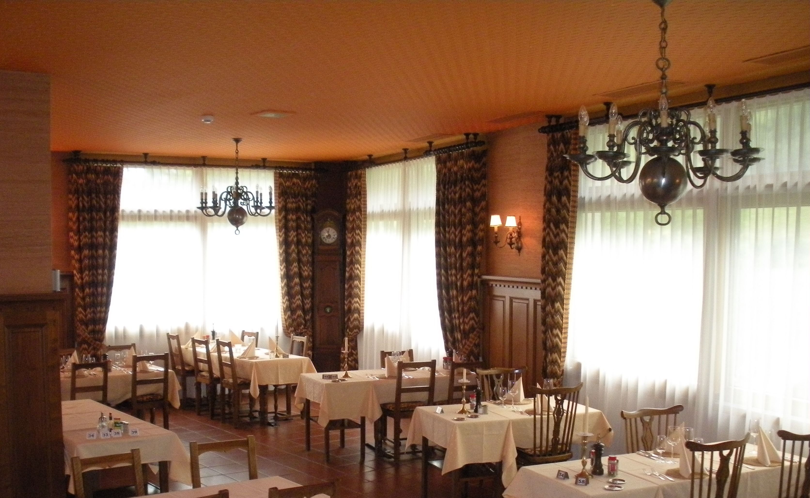Una sala da pranzo con diversi tavoli apparecchiati, un lampadario e una sveglia appesa al muro.