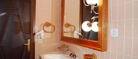 Un baño con lavamanos blanco, puerta de madera y espejo con iluminación.