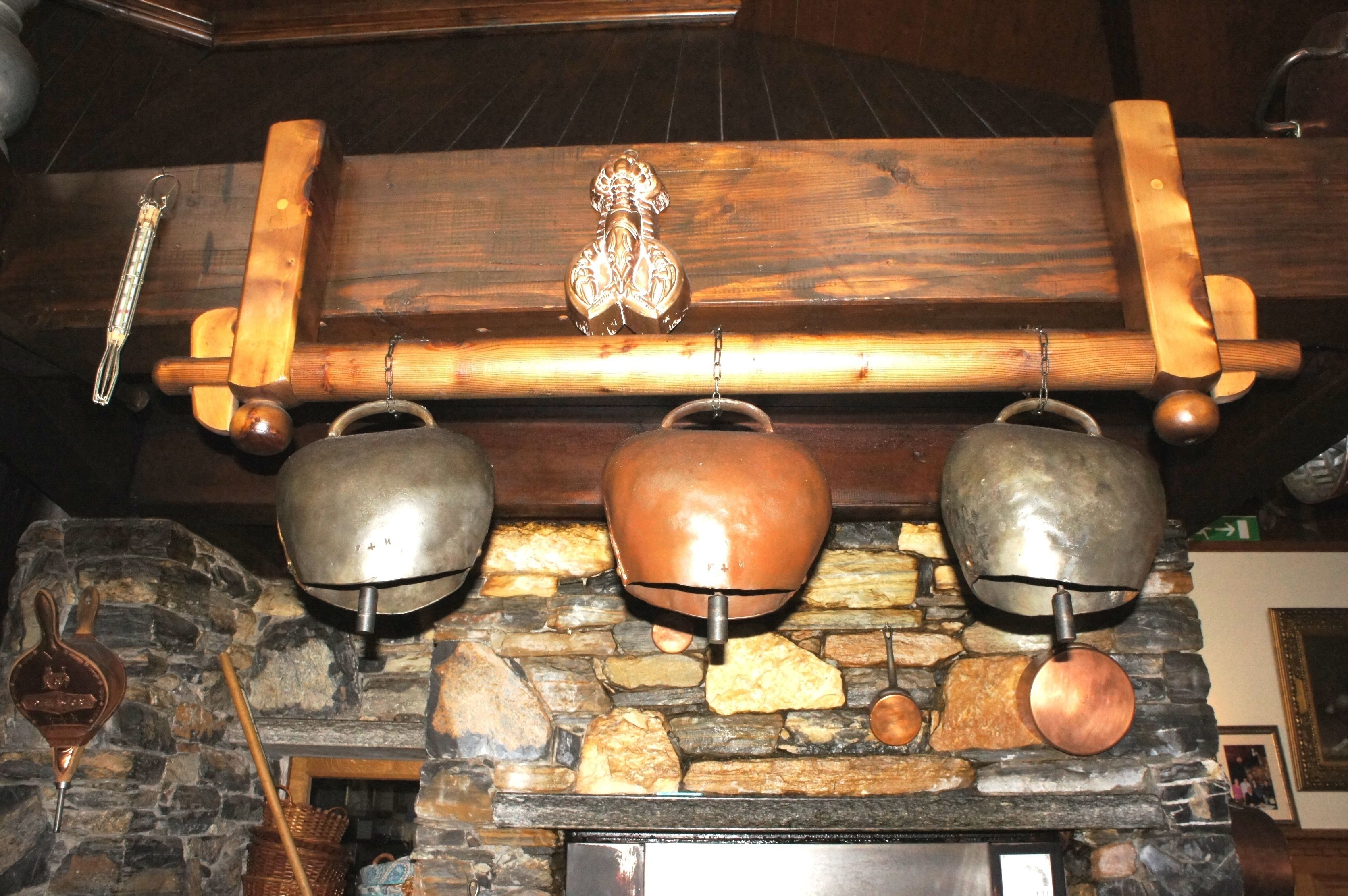Una chimenea de piedra con tres picos de metal colgados encima.