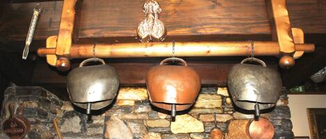 A stone fireplace with three metal kettles hanging above it.