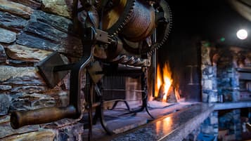A fireplace with a stone wall and a log fire.