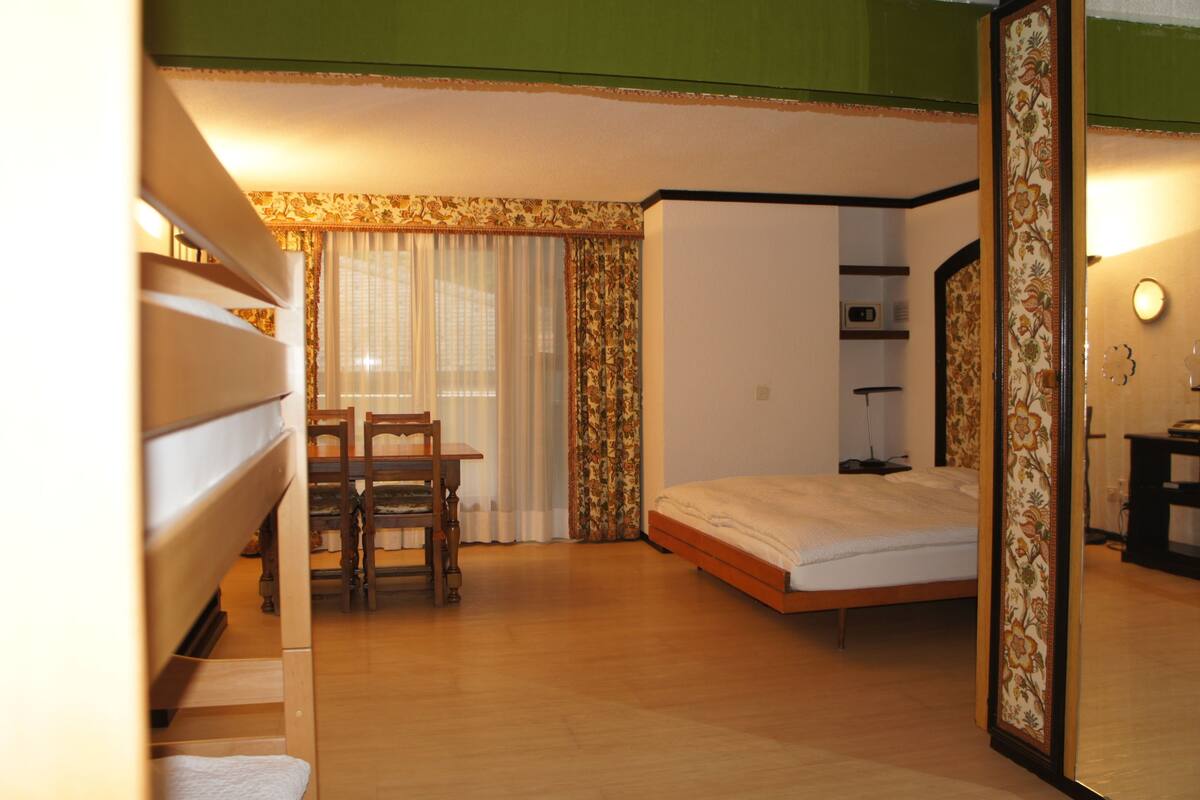 Un dormitorio con cama, una silla, una mesa y un armario.