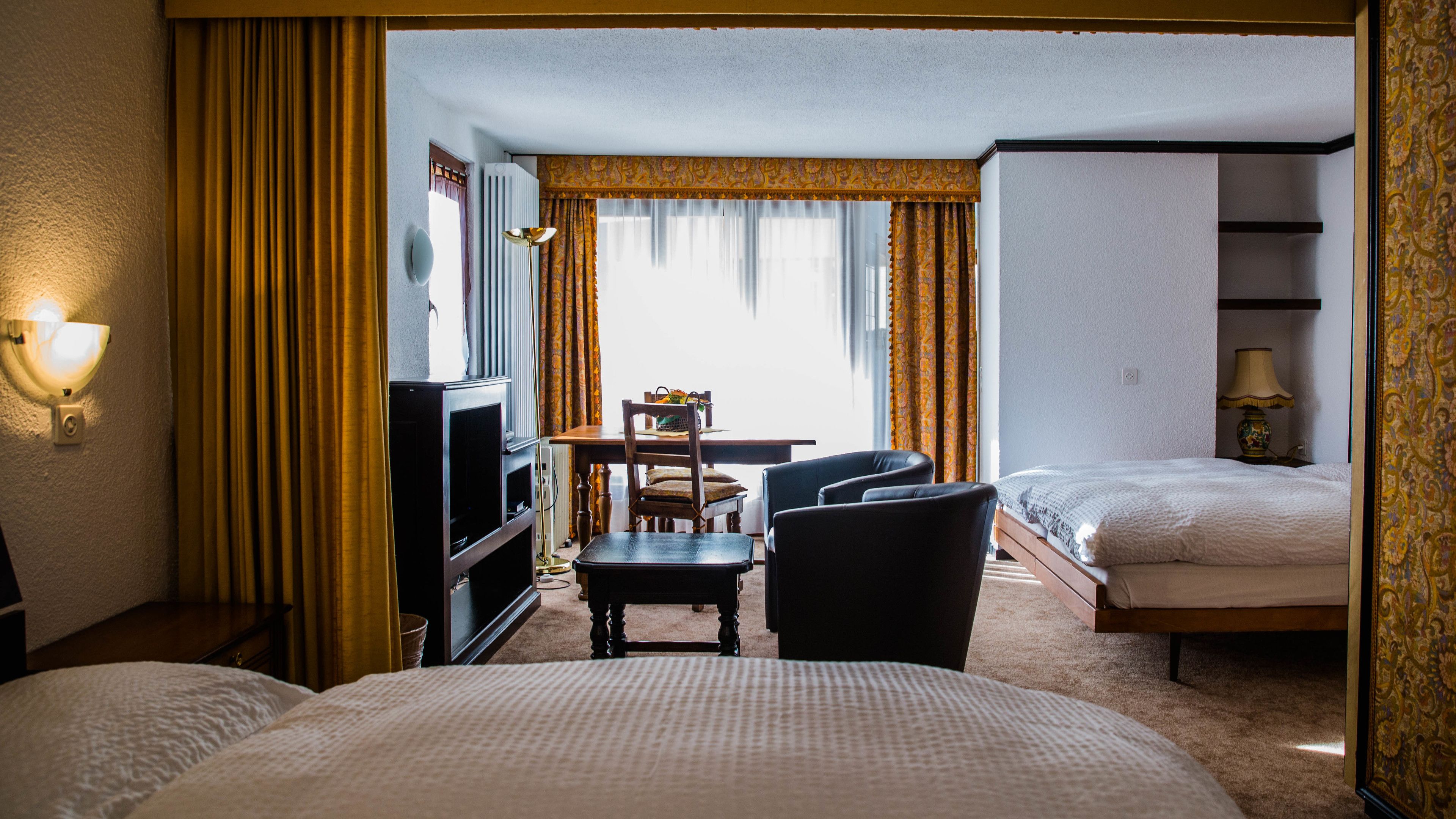 Une chambre d’hôtel avec deux lits, un bureau avec une chaise, une télévision et une lampe.