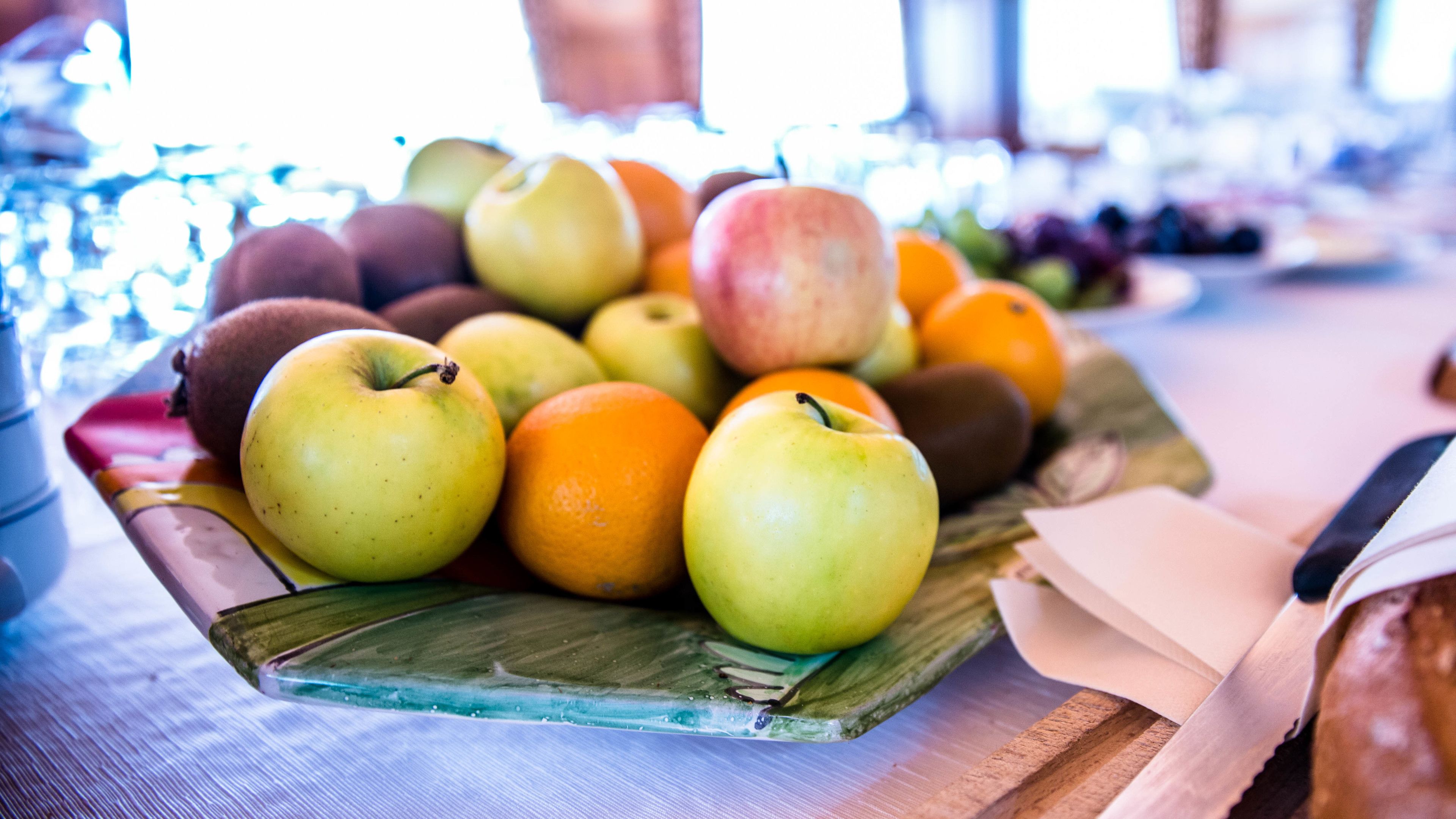 A wooden tray with apples and oranges on a table.