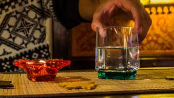 A hand holding a glass of water over a candle holder.