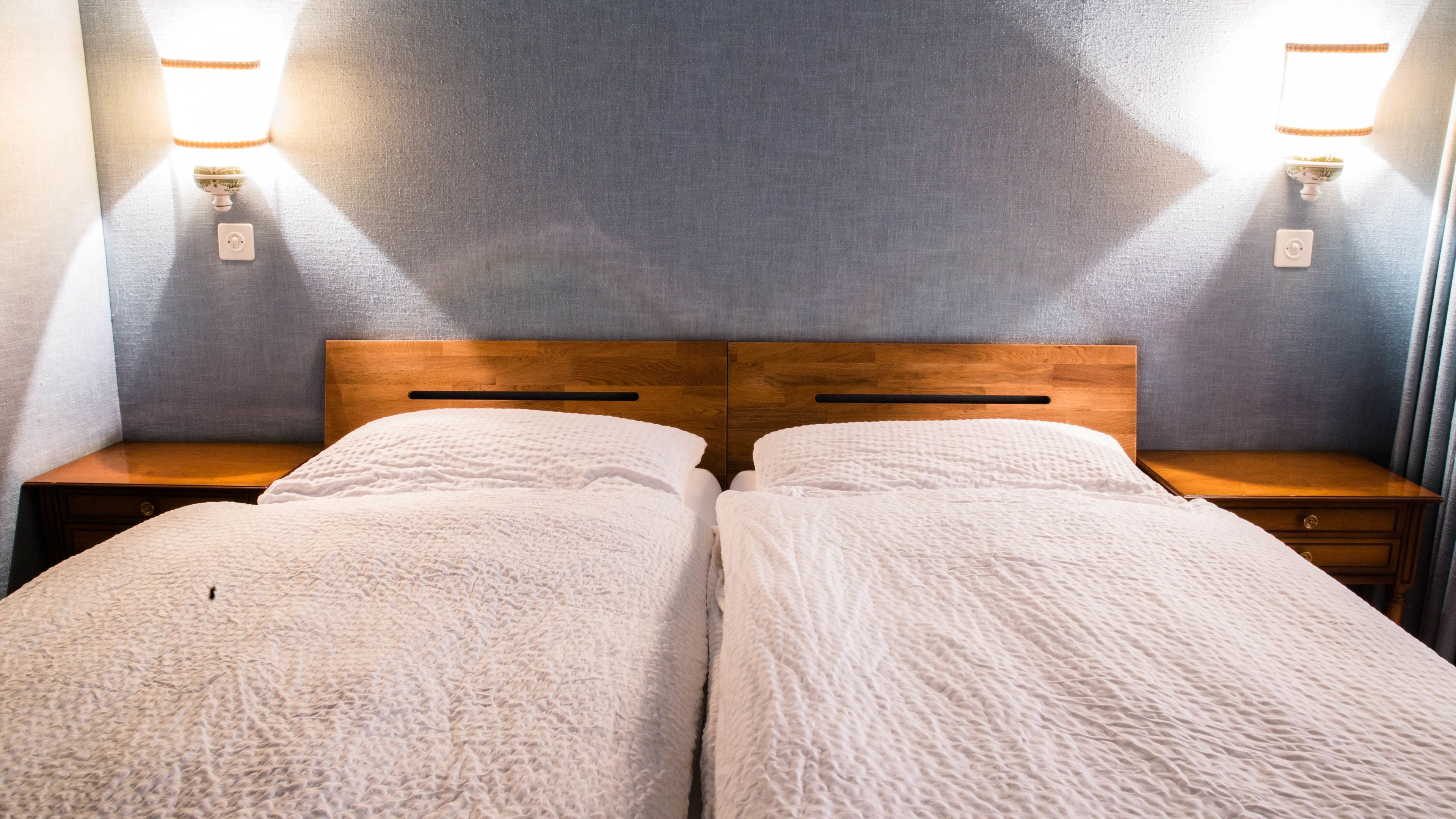 A double bed with a wooden headboard, two bedside tables, and wall-mounted lamps.