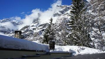 Une montagne enneigée, avec une tour de pierre et un arbre chargé de neige au premier plan.