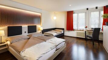 A modern hotel room with a large bed, bedside tables, a desk, and a chair.