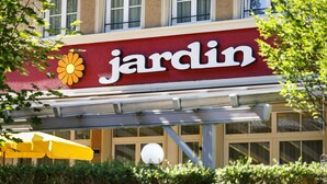 A storefront with a red awning and a flower logo, indicating a garden center. - Hotel Jardin (Bern)