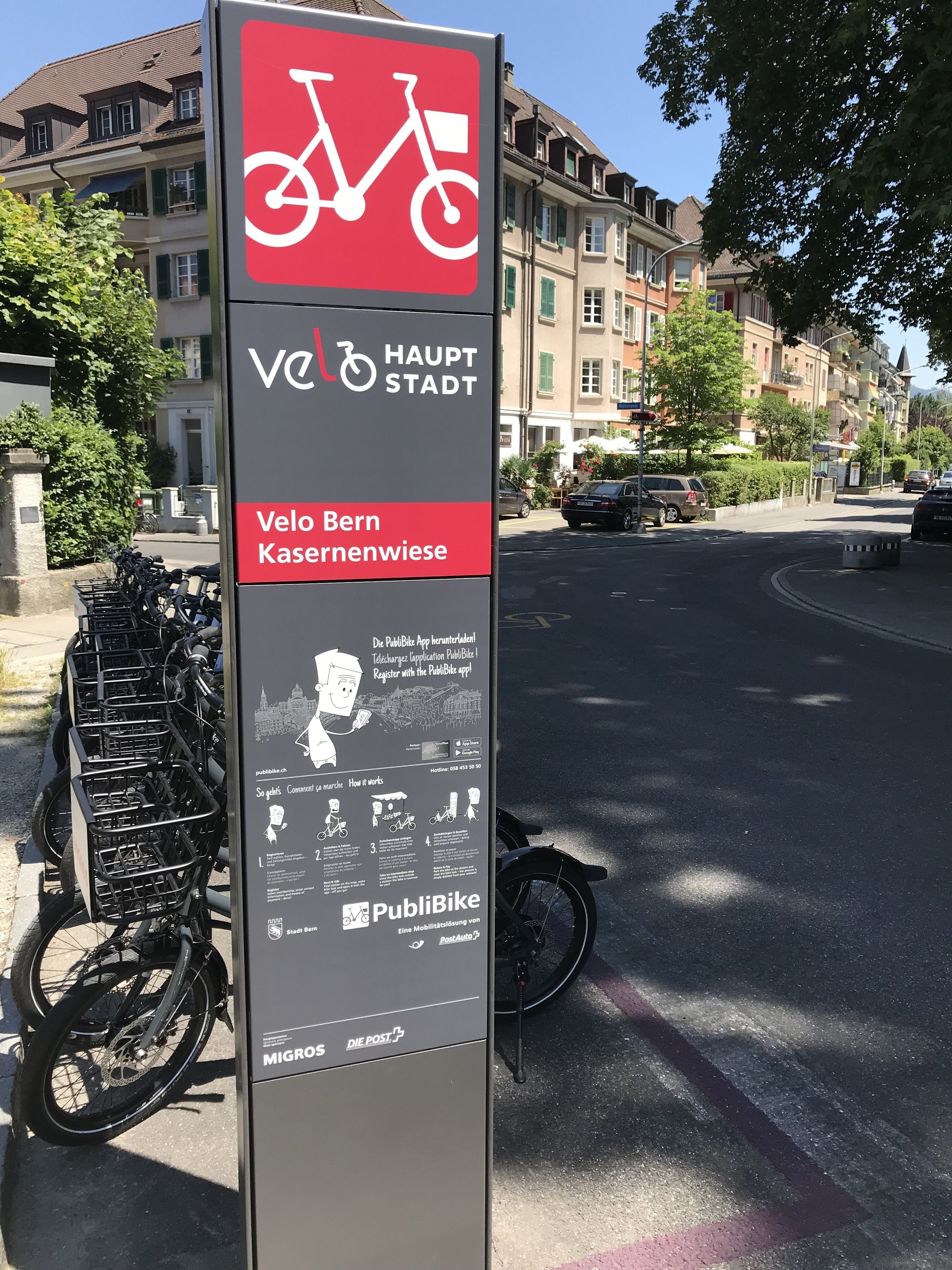 A public bike rental station with a sign for Velo Bern Kasernenwiese, including a map and instructions.