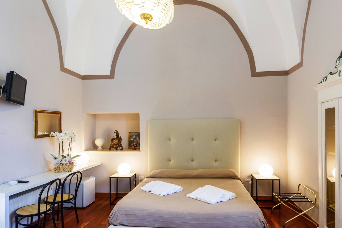 A bedroom with a large bed, bedside tables, a desk, and a chair.