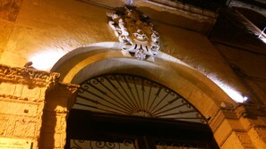 An ornate arched doorway with a decorative fanlight and a stone wall.