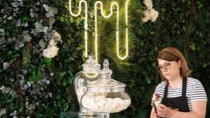 Vitrine de joias com um letreiro de neon, uma pessoa atrás do balcão e uma vitrine de vidro com joias.