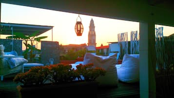 Relax on the rooftop terrace with a view of a historic building and its prominent tower.