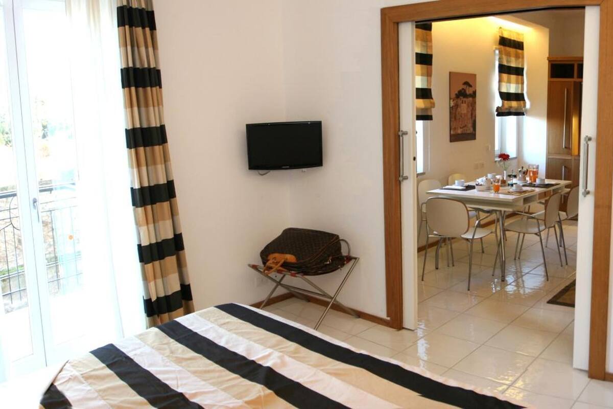 Quarto de hotel com cama, escrivaninha, cadeira, televisão e cofre.