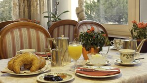 A breakfast table with croissants, a glass of orange juice, and tea set. - Hotel Victoria au Lac (Paradiso)