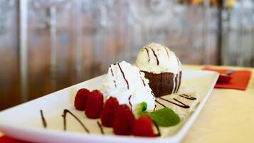 Un plato de postre con helado y frambuesas sobre una vajilla blanca.