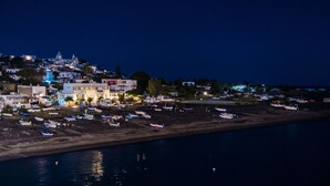 A coastal town at night with buildings, boats, and a beach.