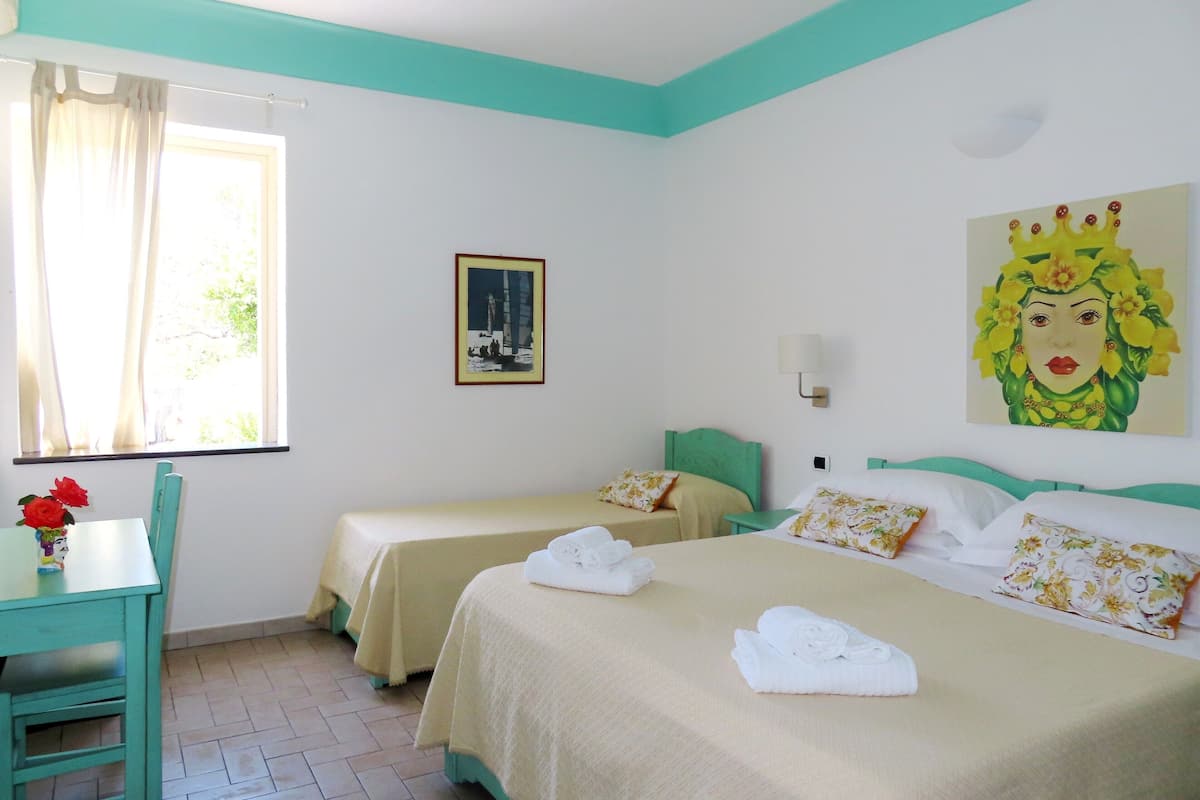 Una habitación de hotel con dos camas, un escritorio y una ventana con cortinas.