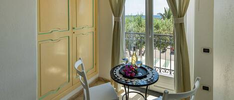 A room with a balcony, a table with a vase of flowers, and a chair.