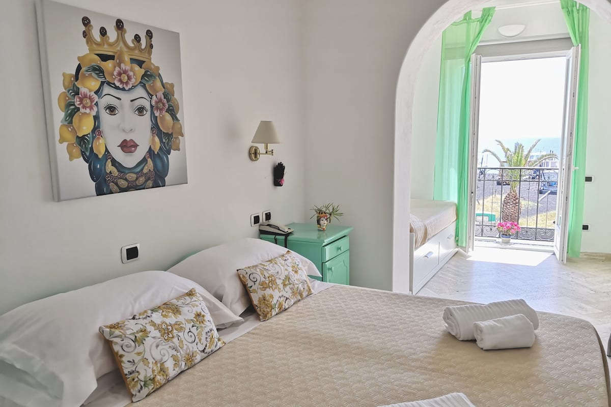 Una habitación de hotel con una cama, una mesita de noche, una lámpara y un cuadro en la pared.