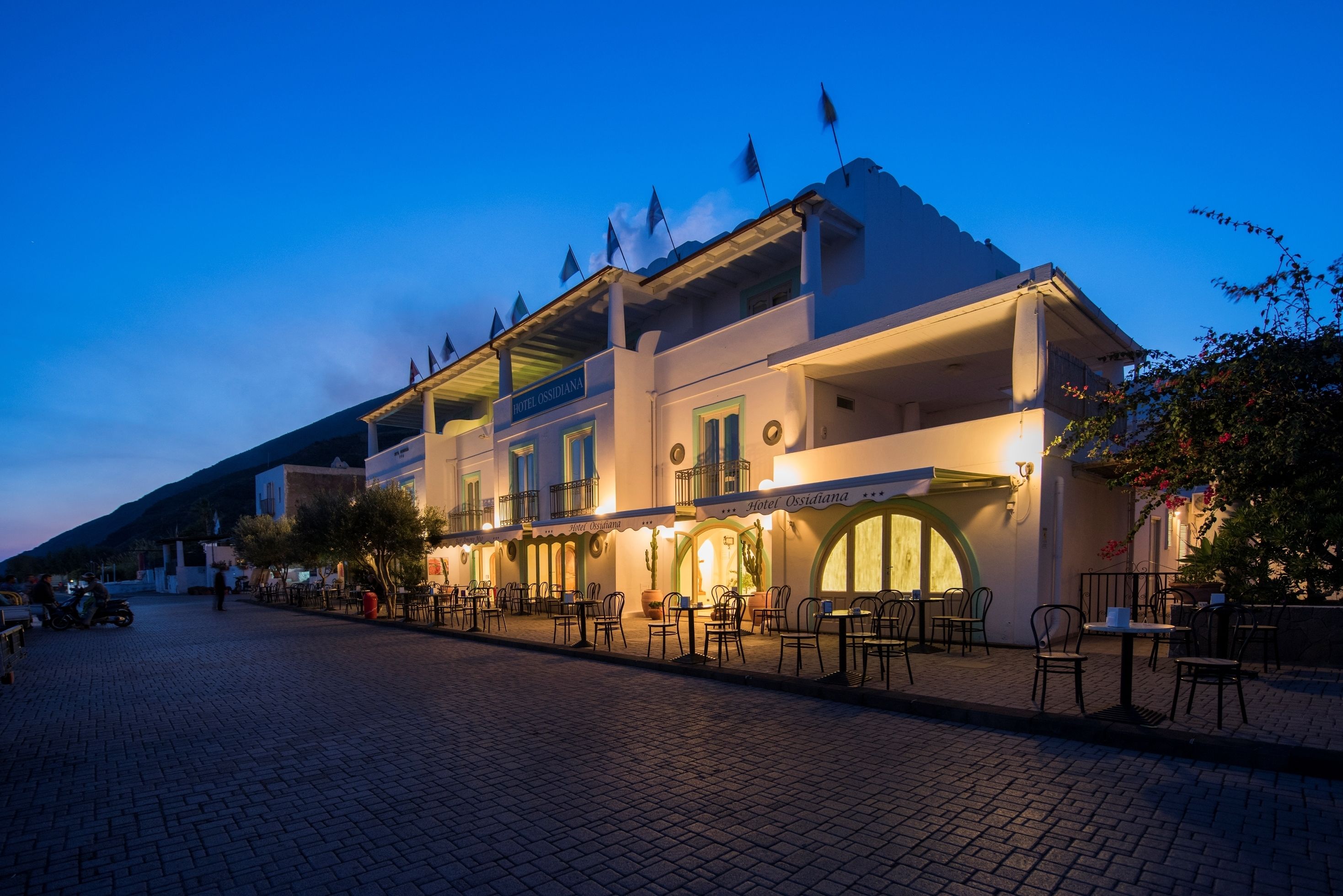 Un hotel con mesas al aire libre y un letrero que dice "Hotel Ossidiana".
