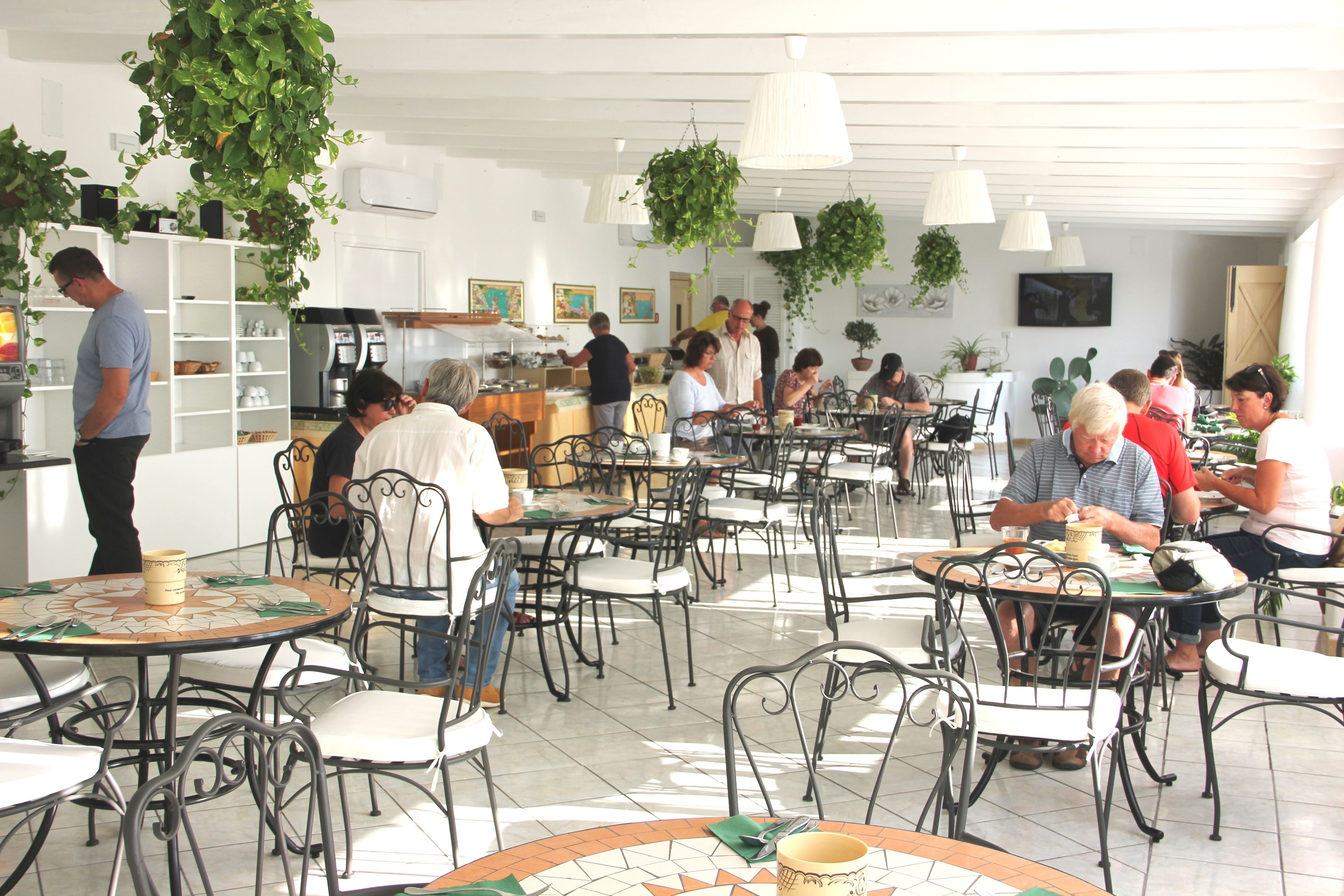 A restaurant with round tables and chairs, some with plants on them.