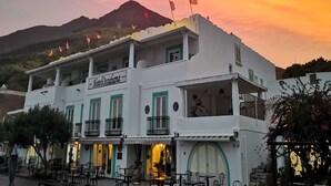 A white building with balconies and a sign reading "Hotel Ossidiana".