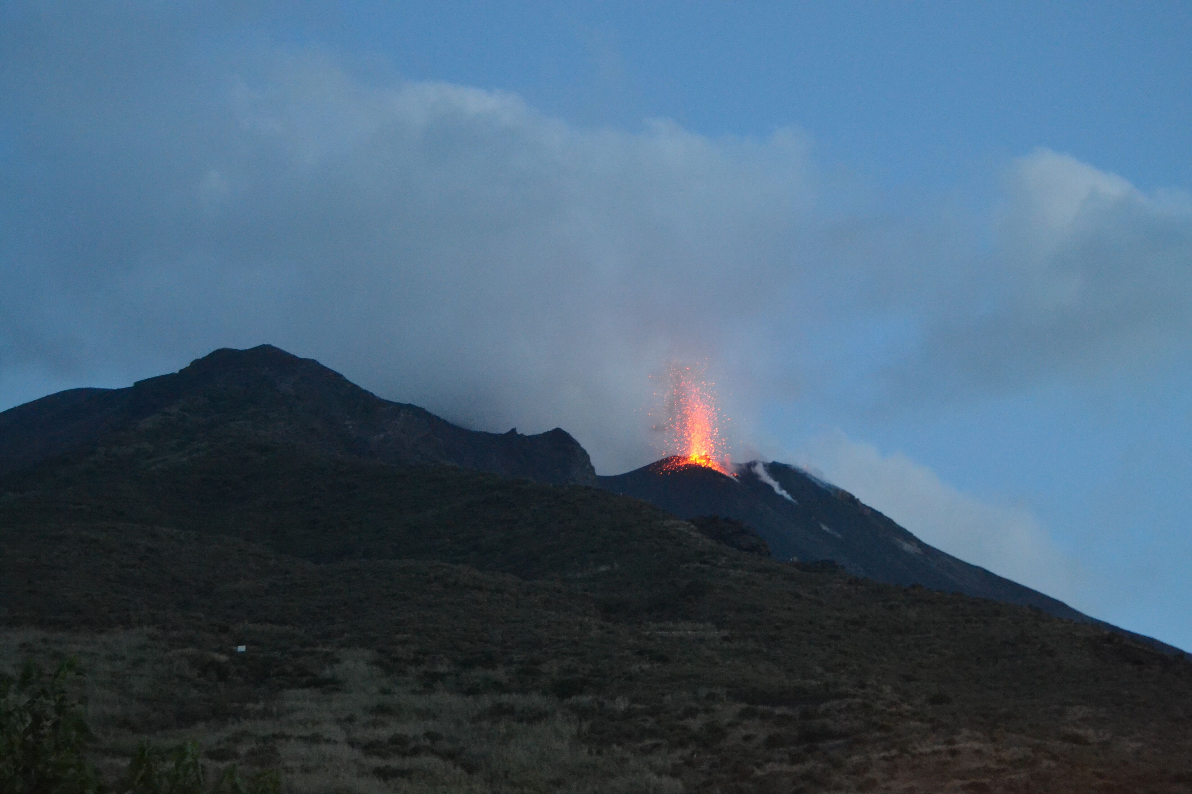 A mountain with a visible volcanic eruption.