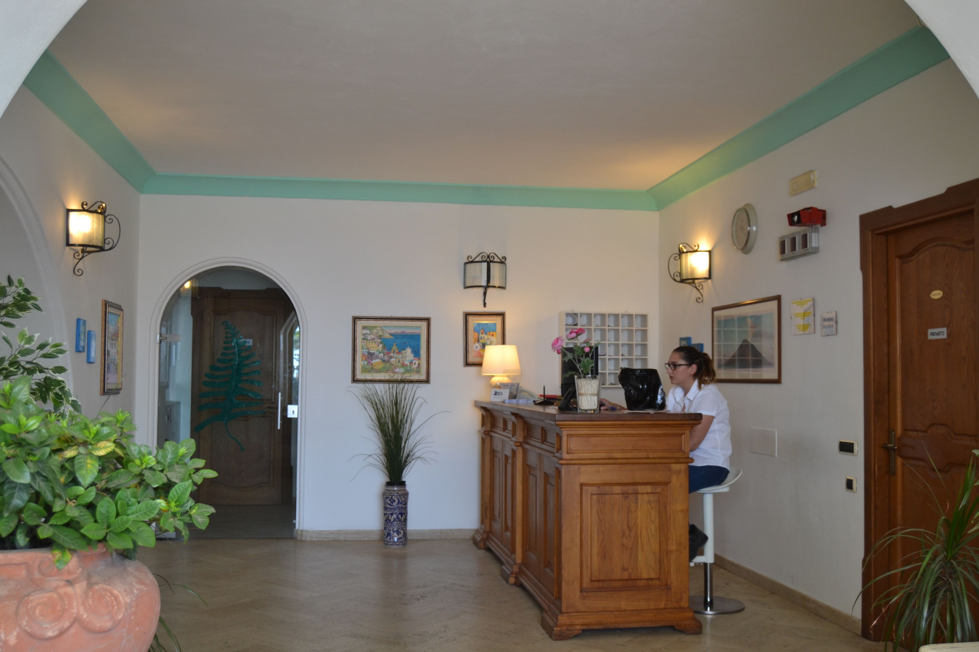 A reception area with a wooden desk, a potted plant, and framed artwork on the walls.