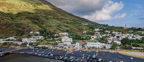 A coastal town with a marina filled with boats, surrounded by hills and residential buildings.