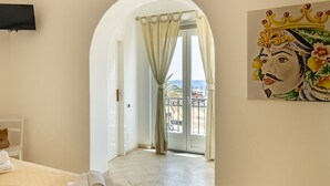 A hotel room with a bed, a painting, a television, and a balcony with a view.