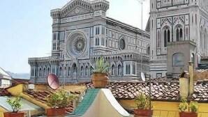 A terrace with outdoor seating and potted plants, overlooking a historic building with intricate architecture. - Residenza Giotto (Florence)