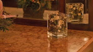 Une salle de bain avec un comptoir en marbre, un miroir et un vase rempli de fleurs.