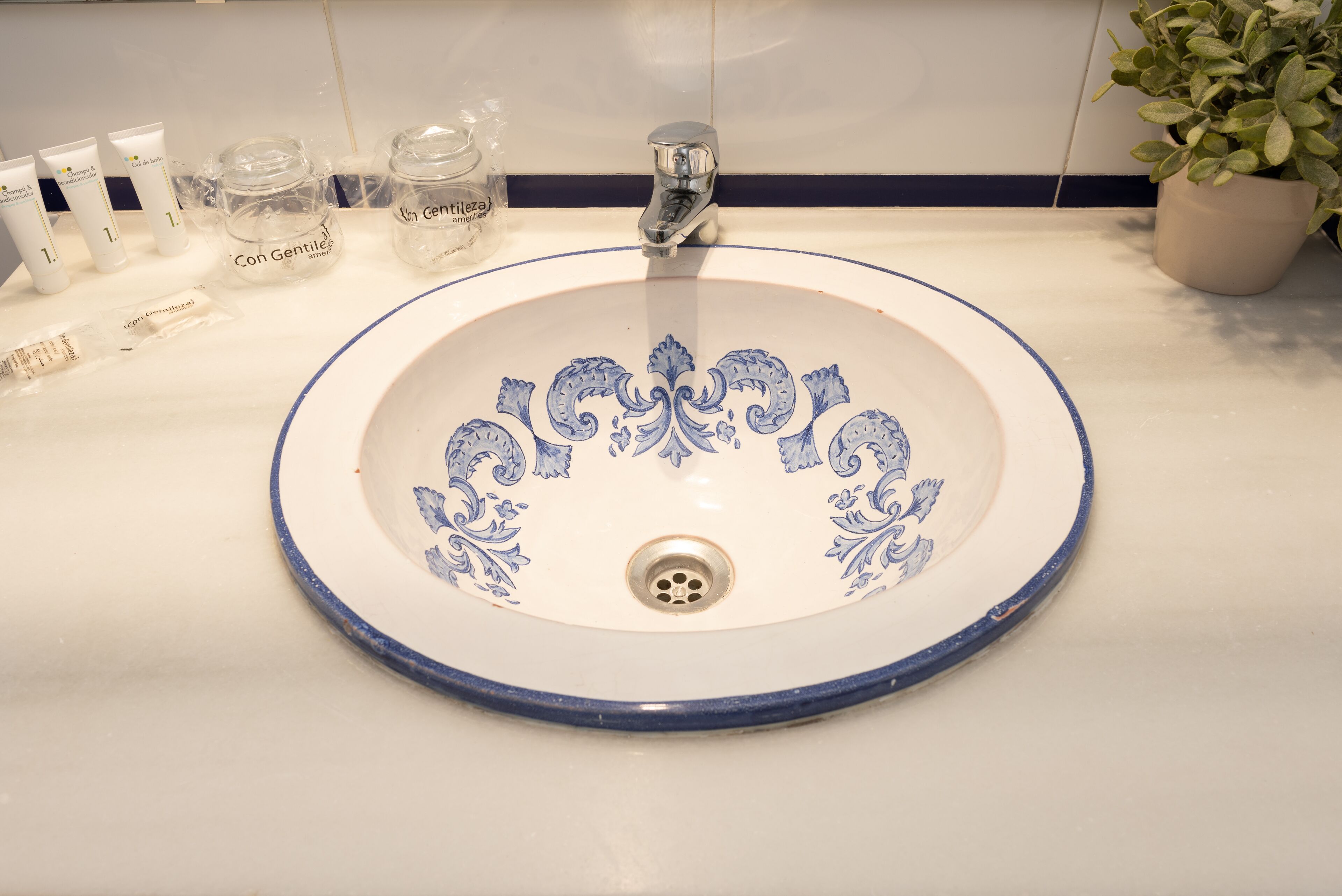 A bathroom sink with a decorative blue pattern, a faucet, and toiletries on the counter.