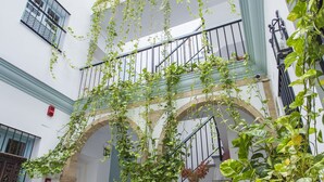 A courtyard with hanging plants, a staircase, and a sign reading "Santa Cruz". - Apartamentos Suites Santa Cruz (Seville)