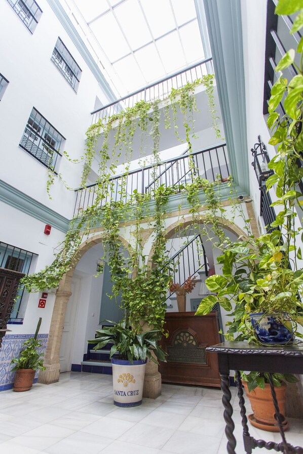 Un patio con plantas colgantes, una escalera y un letrero que dice 'Santa Cruz'.