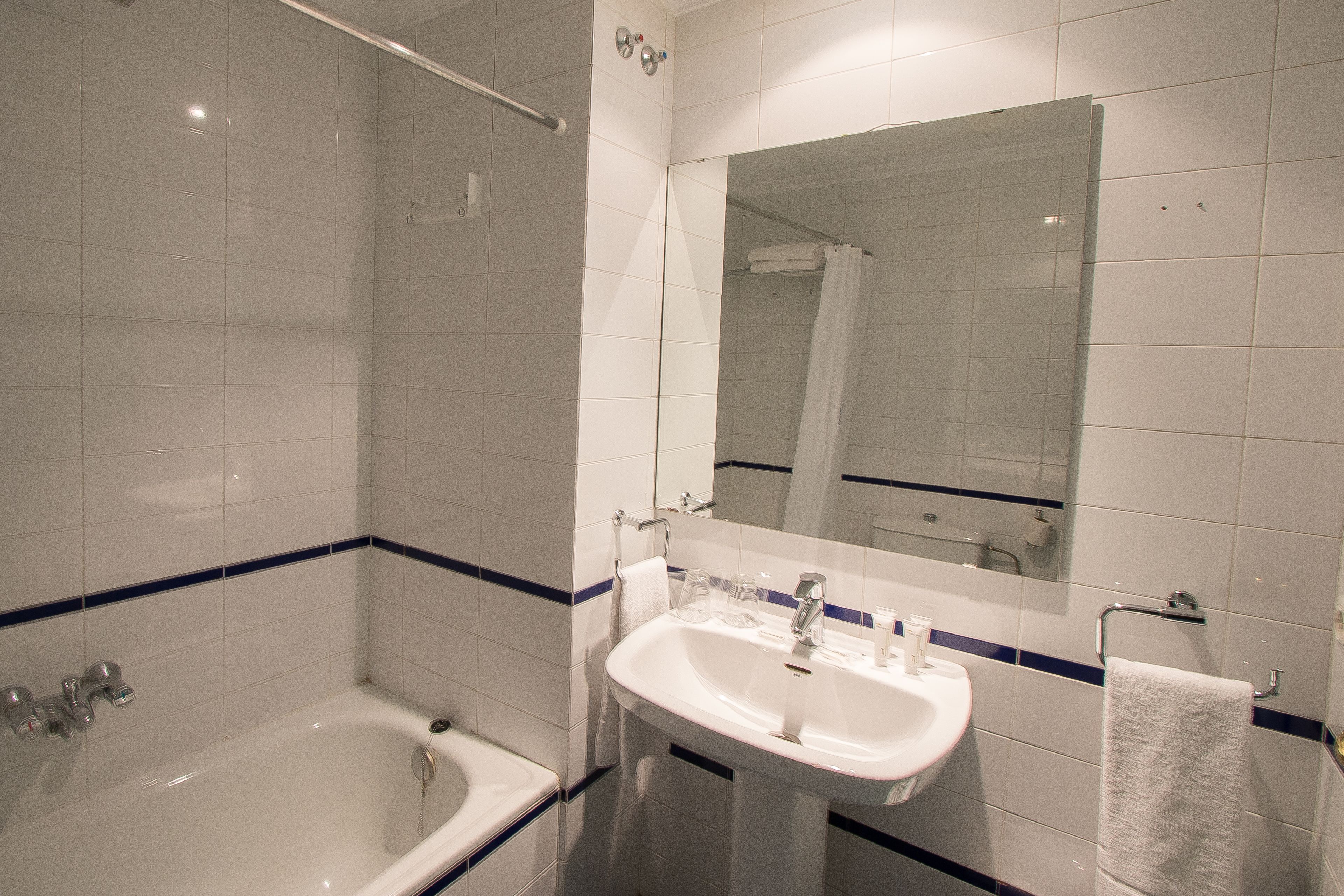 Un baño con bañera, lavabo y espejo.