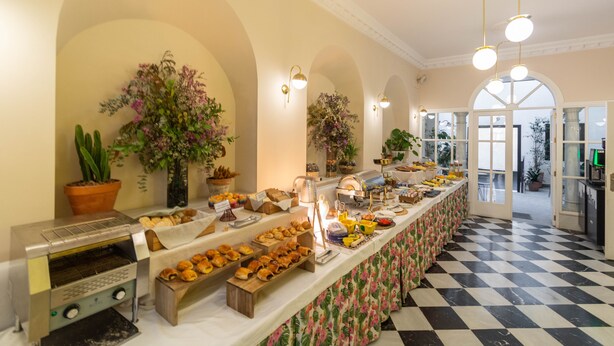 A buffet area with a variety of food items, a coffee machine, and decorative plants. - Apartamentos Suites Santa Cruz (Seville)