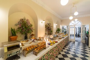 A buffet area with a variety of food items, a coffee machine, and decorative plants. - Apartamentos Suites Santa Cruz (Seville)