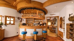 A wooden bar area with stools, shelves with bottles, and a circular wooden structure.