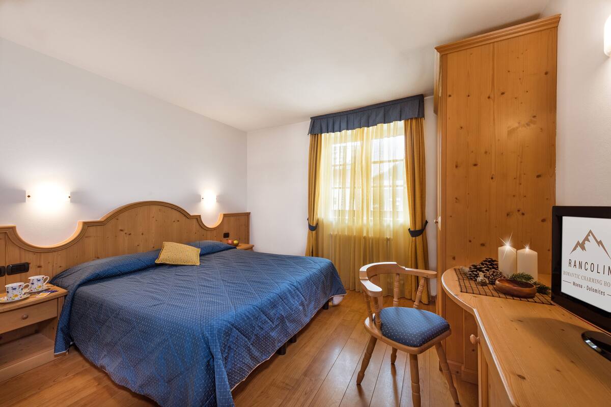 Ein Schlafzimmer mit einem Bett, einem Nachttisch aus Holz, einem Sessel, einem Schreibtisch und einem gerahmten Schild.