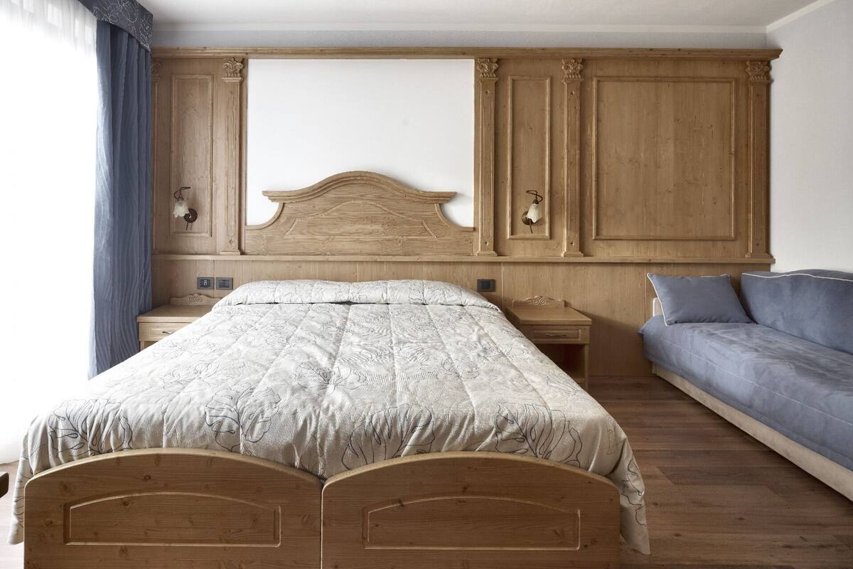 A bedroom with a wooden bed, a nightstand, a dresser, and a sofa.