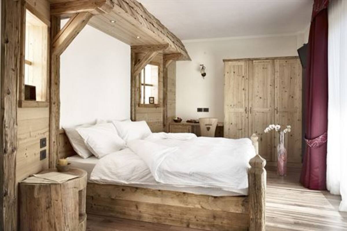 A wooden bed with white bedding in a room with wooden walls and floors.