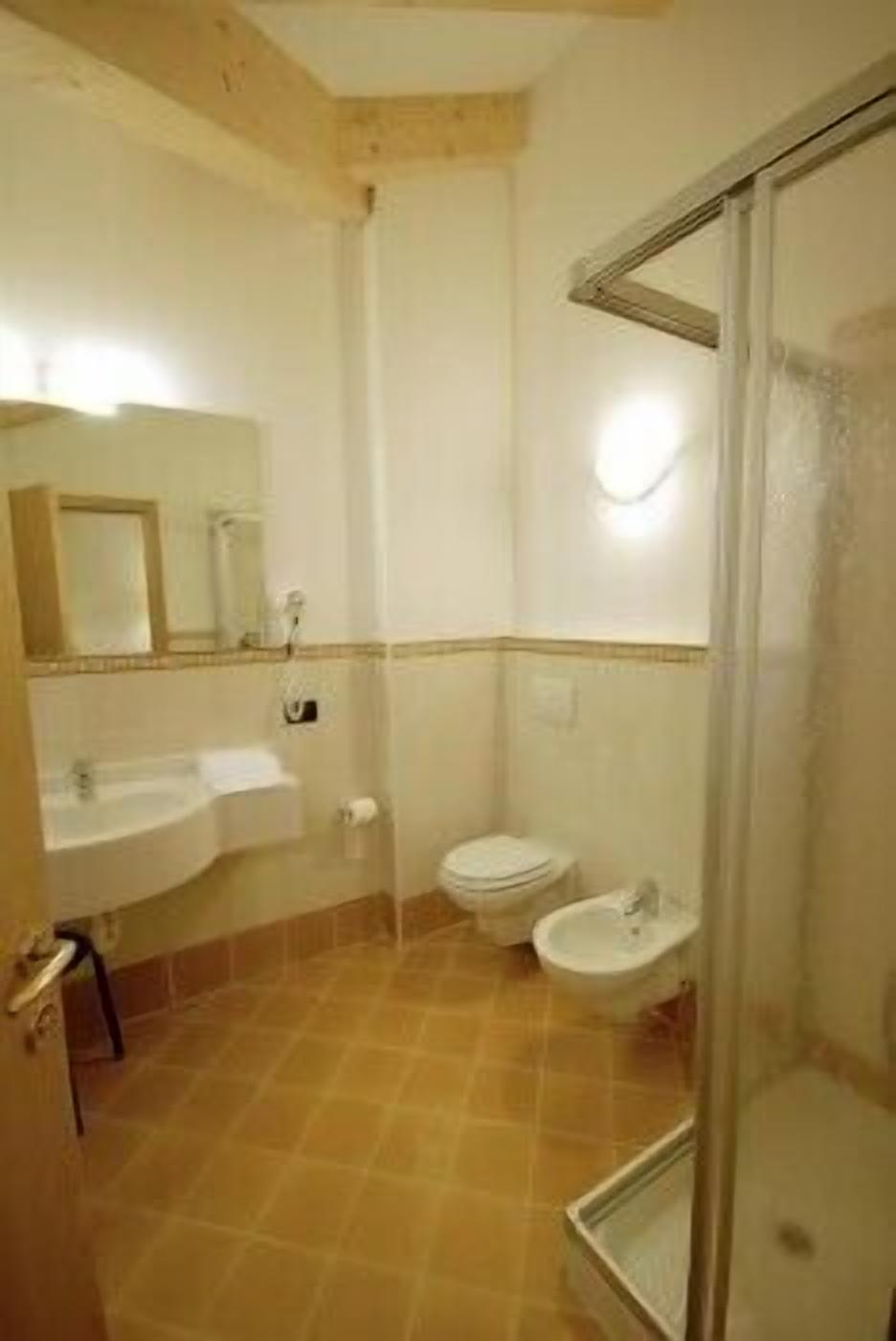 A bathroom with a sink, toilet, bidet, and a glass shower enclosure.